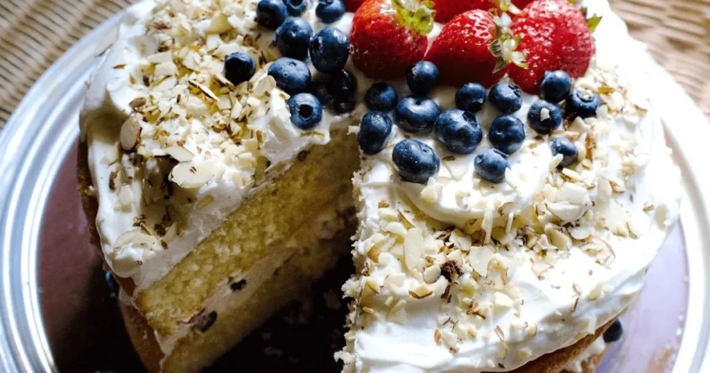 Coffee cake slice with cinnamon crumb topping on a plate next to a steaming cup of coffee.