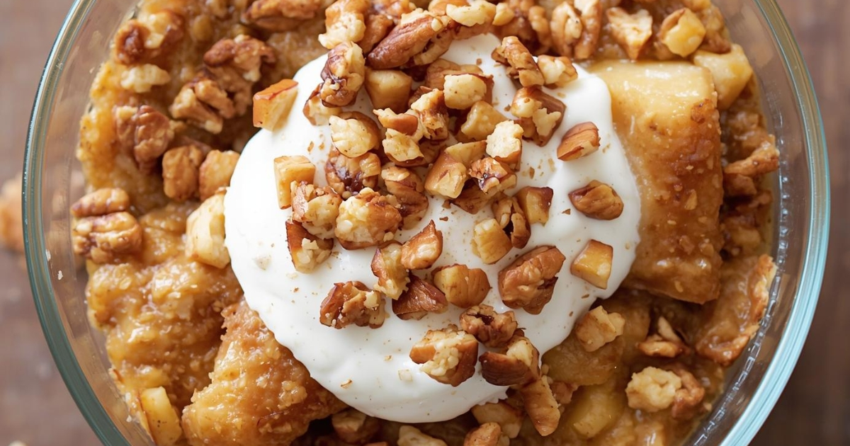 Apple crisp layered over Greek yogurt with granola and walnut topping in a glass bowl.