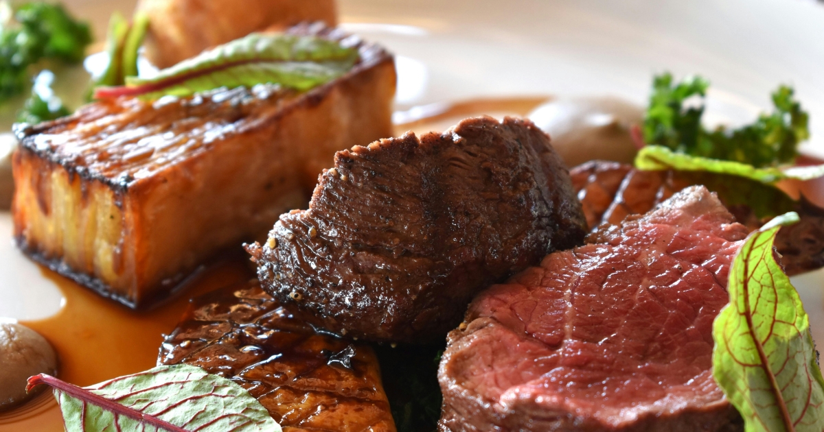 Tender, juicy beef slices with a rich sauce, served with roasted vegetables and fresh herbs on a plate.