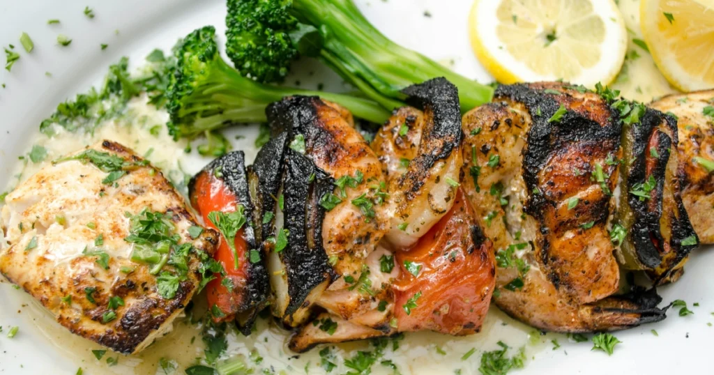 Chicken tenders sizzling on a grill pan with visible smoke and char marks.