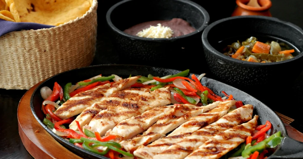 Golden grilled chicken tenders served on a rustic plate with fresh garnish and lemon slices.