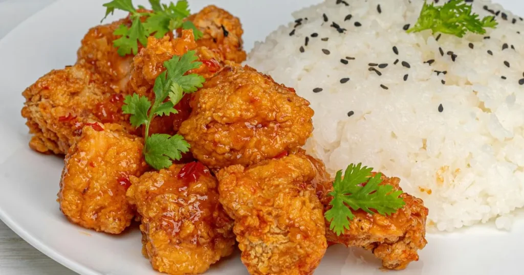 Steaming bowl of beef tips and rice with thick gravy and garnish