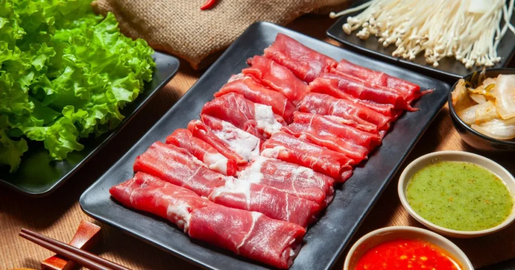 Plate of beef rolls with enoki mushrooms, garnished and ready to eat with a savory glaze.