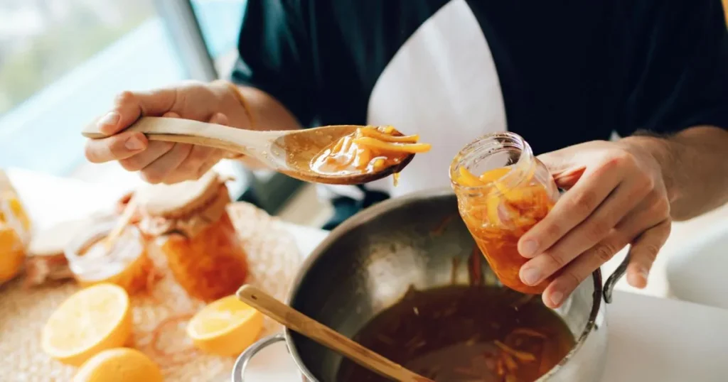 Fresh oranges beside a bowl of orange sauce highlighting its natural citrus ingredients.
