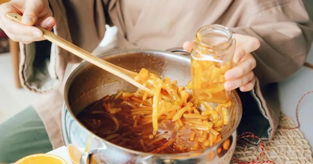 A spoon lifting thick orange sauce with visible glossy texture and steam rising.
