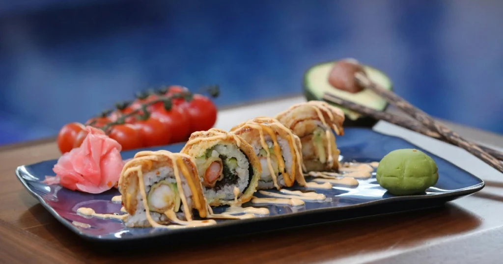 A plate of shrimp and vegetable tempura served with a small dipping bowl of glossy sauce.