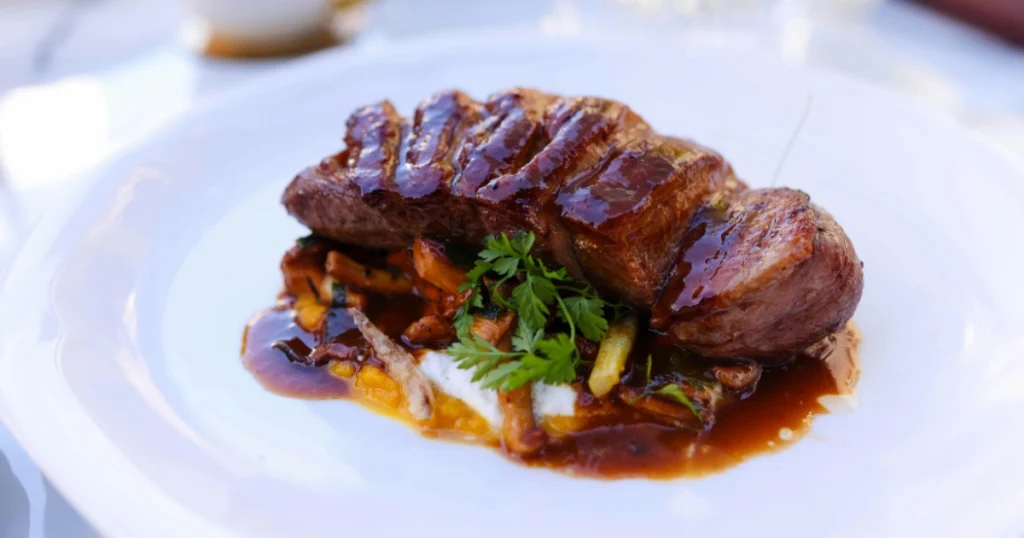 Elegant plated duck dish with sauce drizzle, styled like a restaurant presentation.