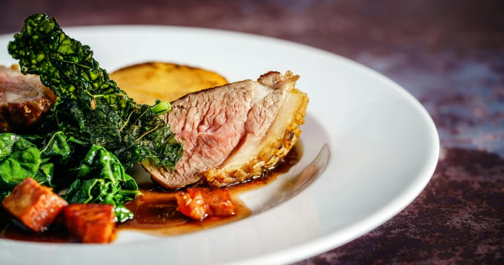 Finished duck dish served with sauce, garnished and ready to eat on a dining plate.