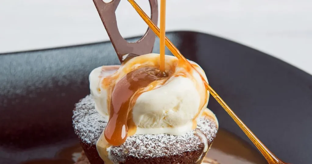 Caramel sauce being poured over a stack of pancakes topped with berries.