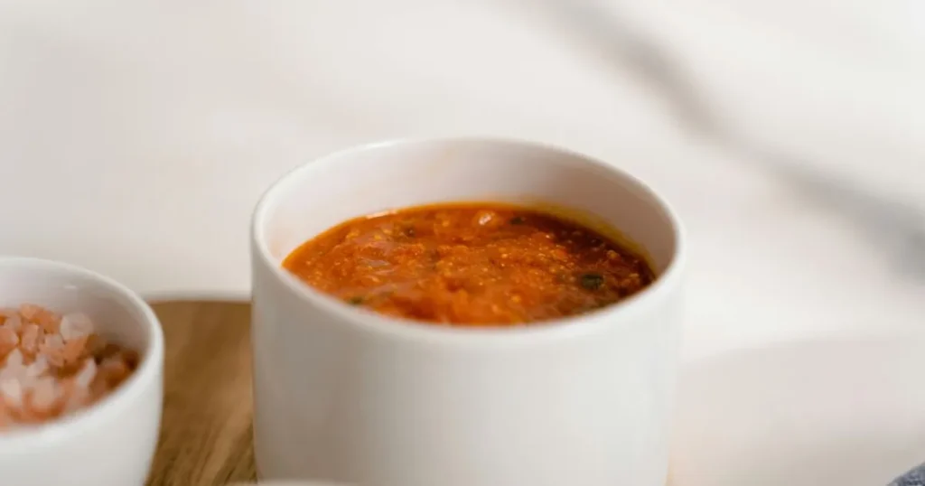 Ingredients like peanut butter, garlic, and sauce neatly arranged next to a finished bowl of peanut sauce.