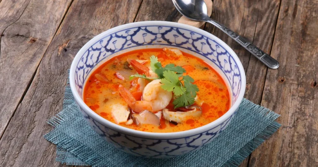 Instant Pot releasing steam with a freshly cooked soup inside a bowl nearby.