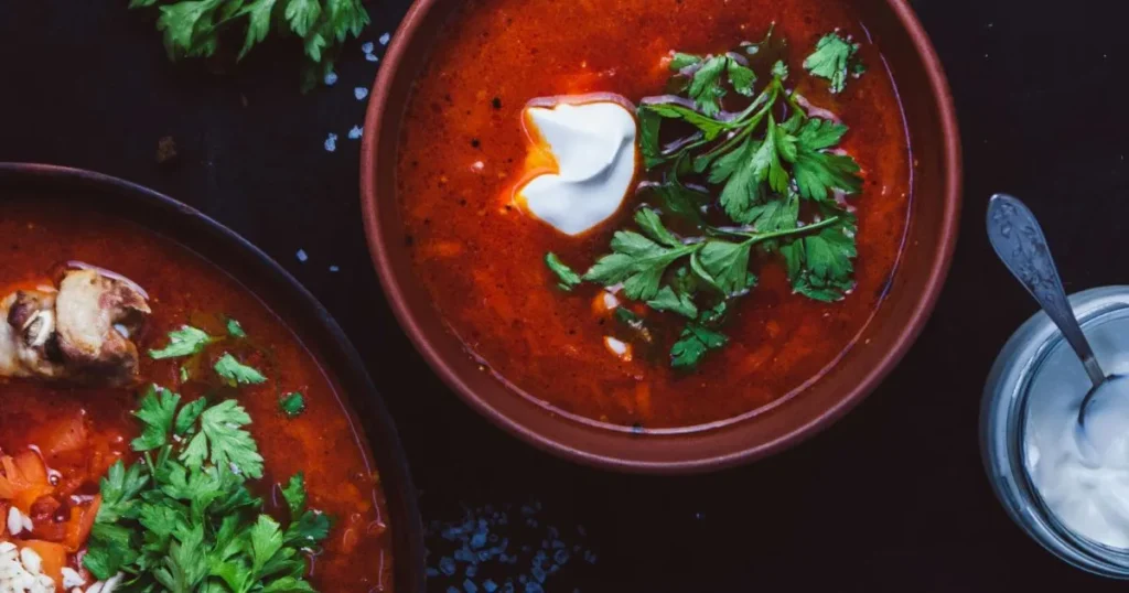 A spoon lifting steaming chicken tortilla soup with visible beans, corn, and chicken pieces.