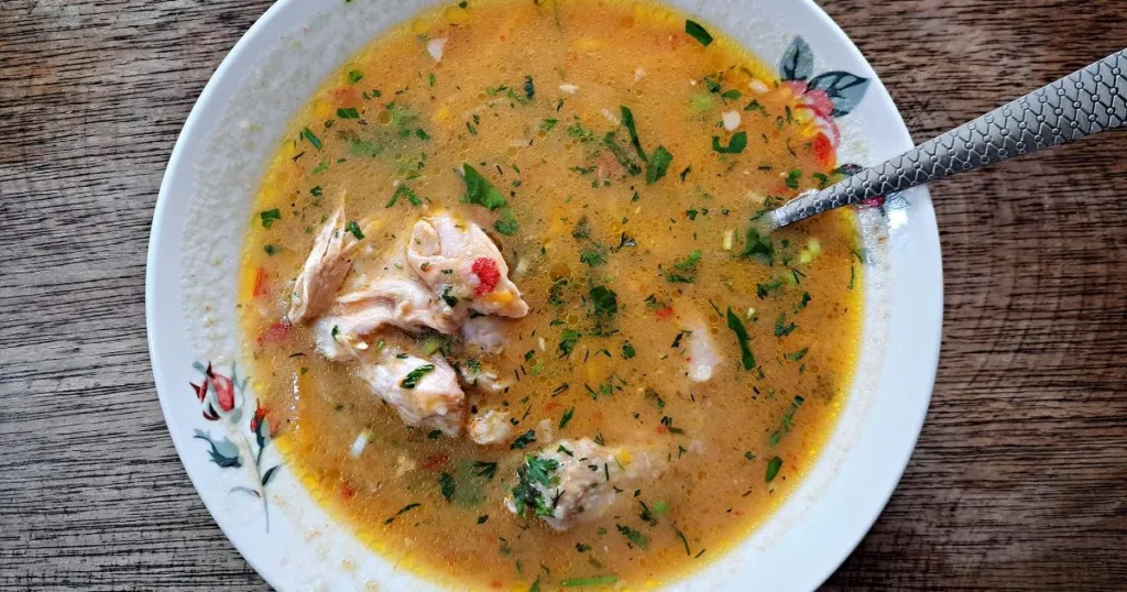 A healthy bowl of low sodium chicken noodle soup with noodles, chicken, carrots, celery, and parsley in a clear broth.