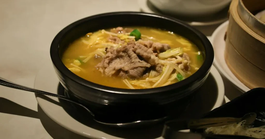 A hearty bowl of beef soup bones soup with tender vegetables, fresh parsley garnish, and crusty bread on the side.