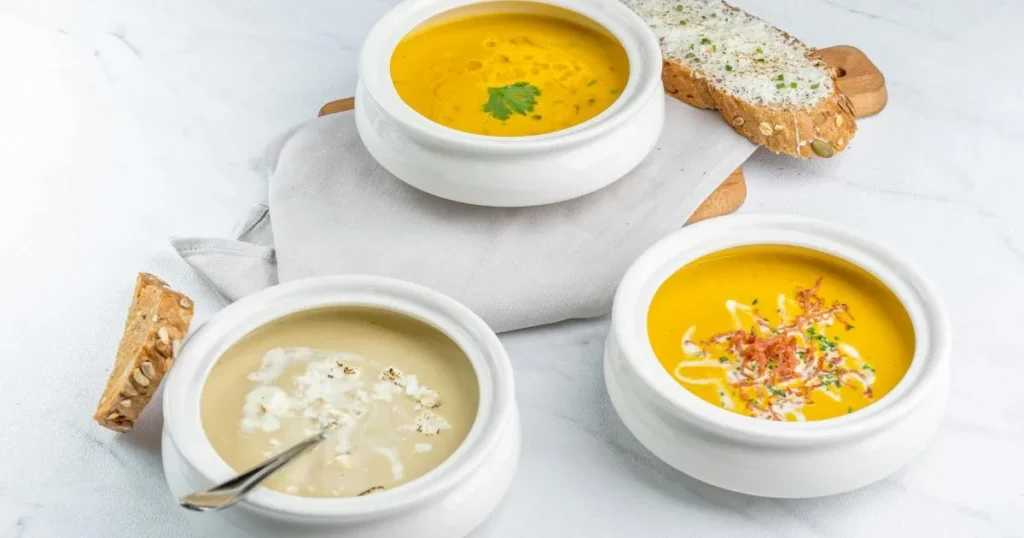 Close-up of a hearty gluten free chicken soup in a white bowl, filled with chicken pieces, carrots, and broth.