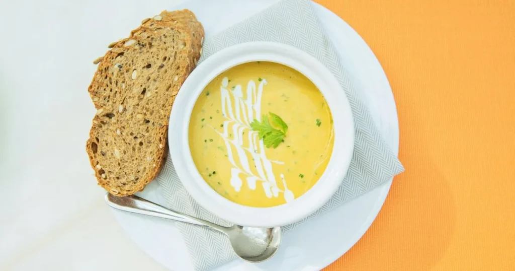 Close-up of chicken soup with vegetables and gluten free noodles in a white bowl.