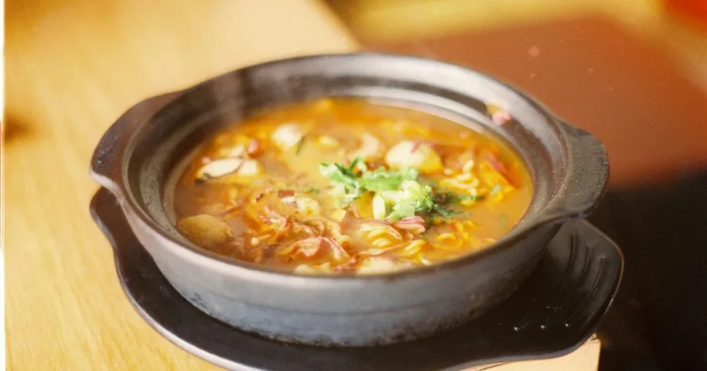 Homemade sizzling rice soup served in a ceramic bowl with mushrooms, napa cabbage, carrots, and crispy rice topping.