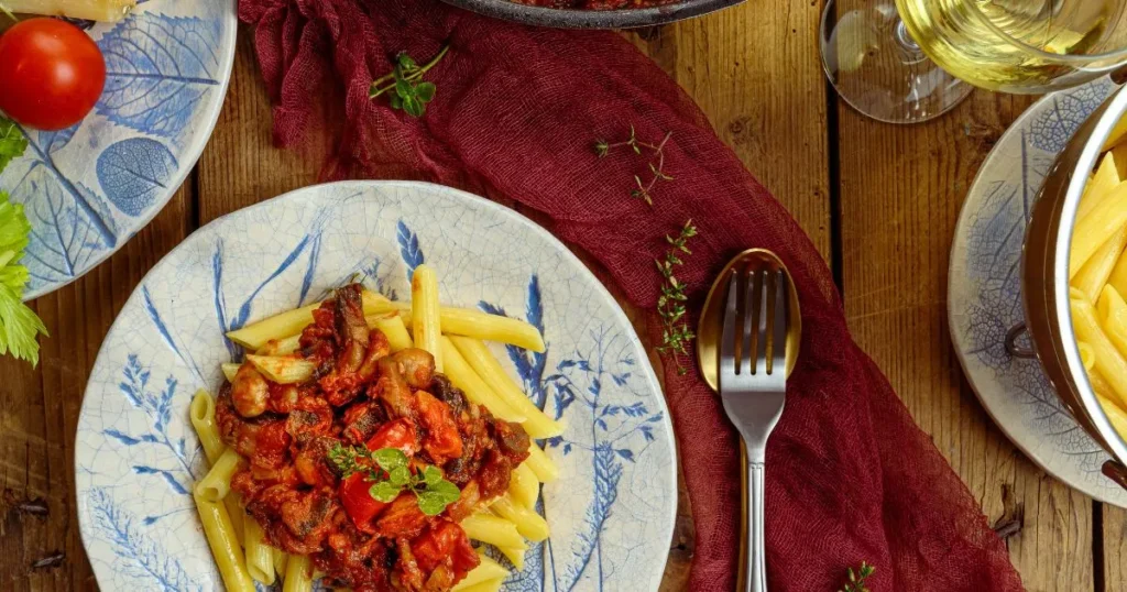 Warm bowl of creamy Italian casarecce pasta with basil leaves and parmesan cheese on top.