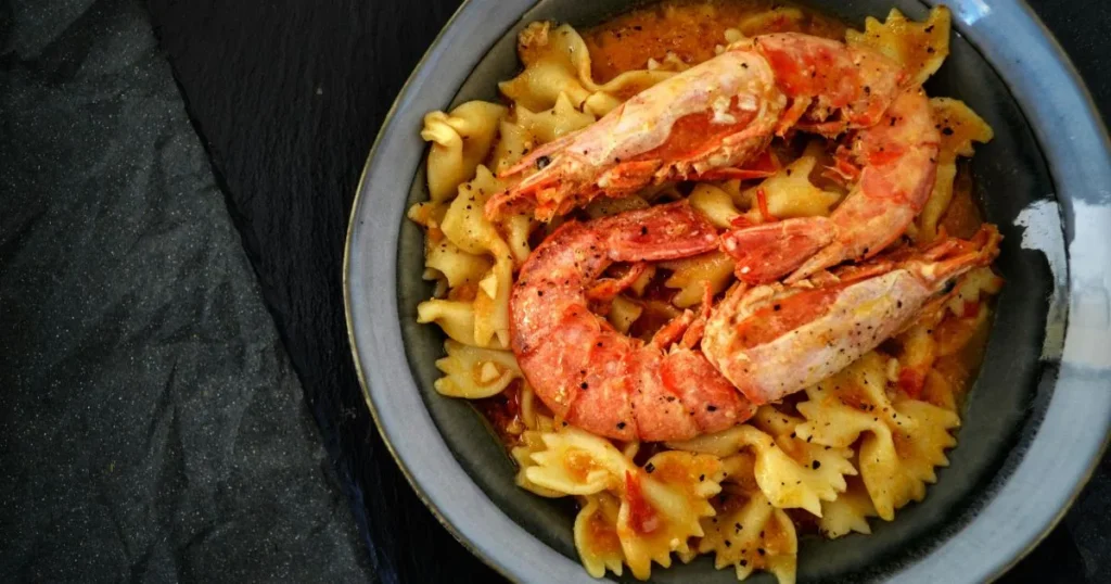 Radiatori pasta coated in creamy garlic parmesan sauce with sausage and fresh parsley garnish.