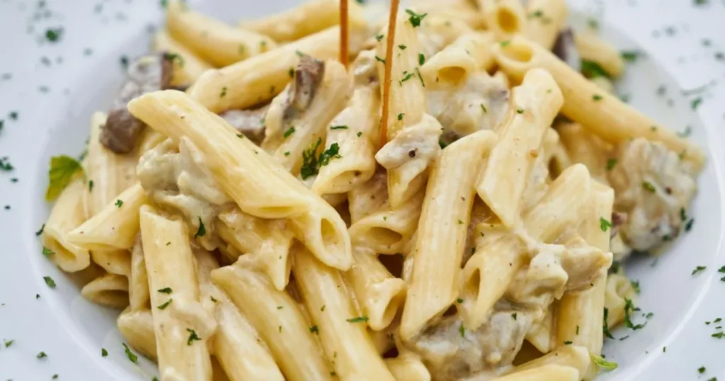 Bowl of creamy Cajun sausage pasta topped with grated Parmesan and fresh parsley.