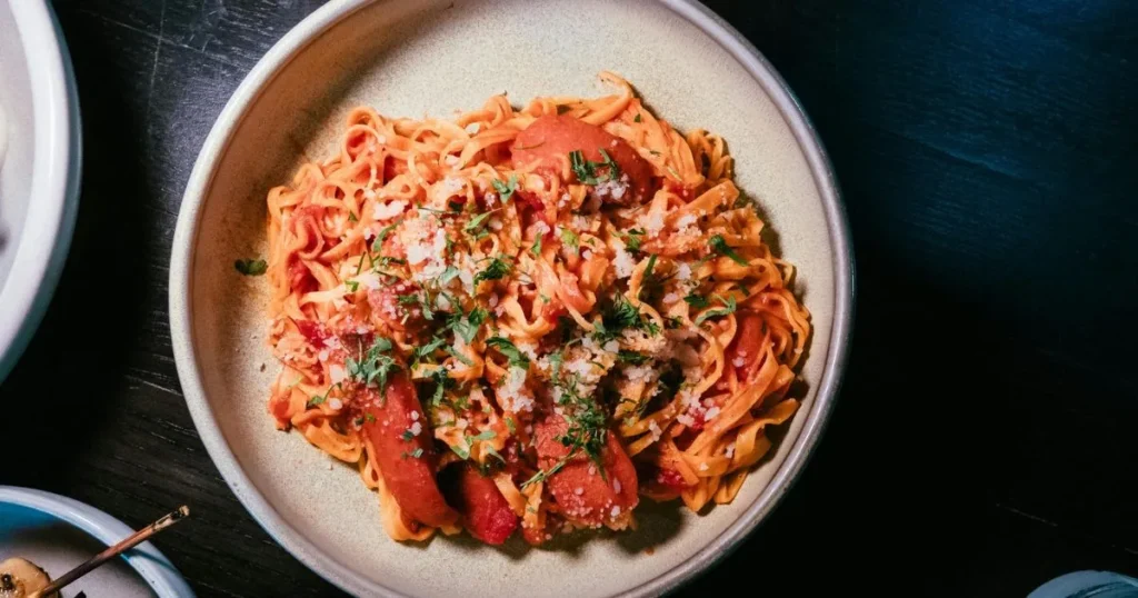 Warm bowl of Cajun sausage pasta with creamy sauce and fresh parsley on top.