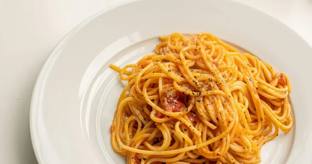 Spaghettini pasta garnished with parsley and parmesan.