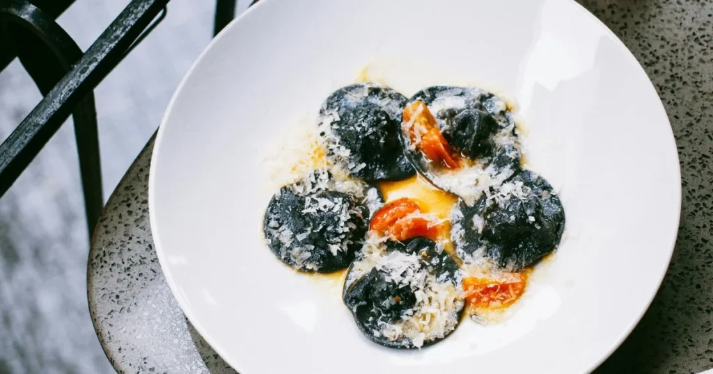 Close-up of black calamari ink pasta with garlic butter sauce and calamari rings.