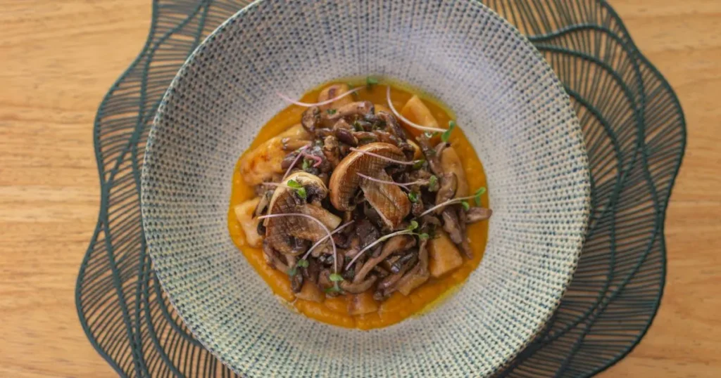 Mediterranean calamari ink pasta garnished with parsley and lemon wedges on a white plate.