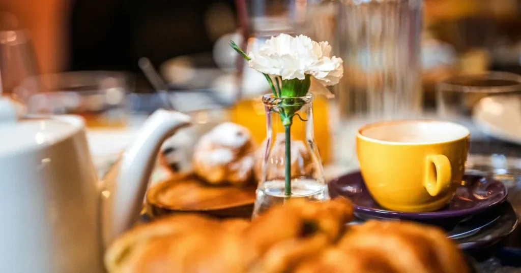 An elegant Italian breakfast setup with espresso cups, warm cornetti, strawberries, and powdered sugar.
