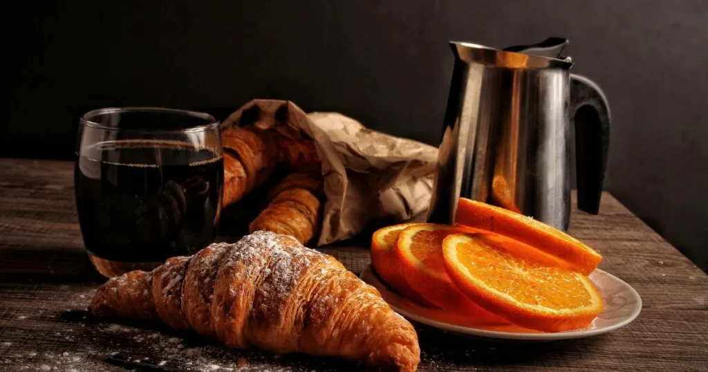 Italian breakfast pastries served with espresso, fresh fruit, and honey on a rustic wooden table.