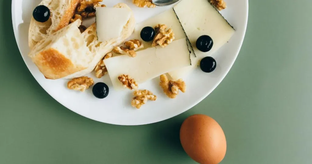 Mediterranean-style Spanish breakfast with tomato toast, herbs, eggs, and olive oil beside fresh fruit and coffee.
