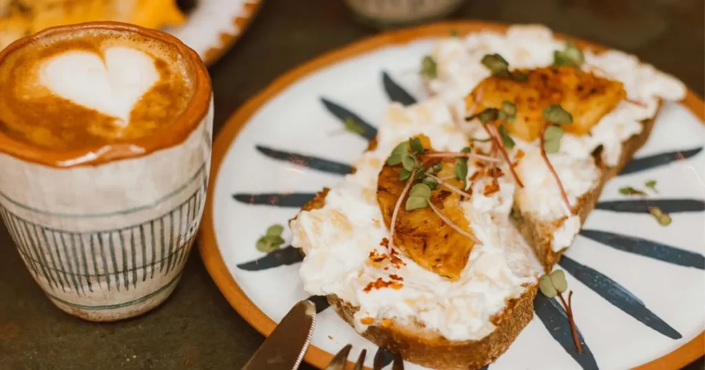 Close-up of crispy Spanish tomato toast drizzled with olive oil and served with eggs on a rustic breakfast plate.