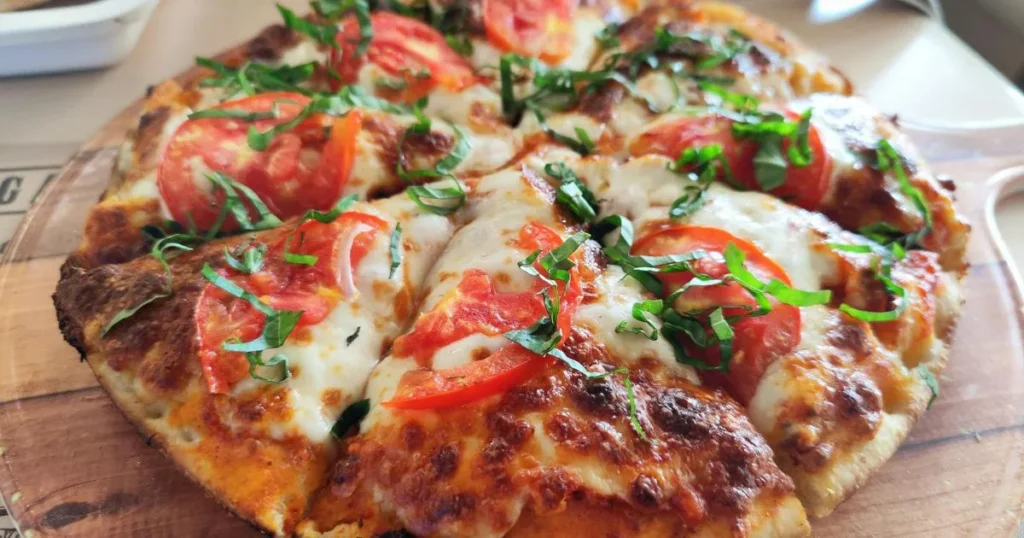 Close-up of cheesy breakfast pizza topped with eggs and sausage.
