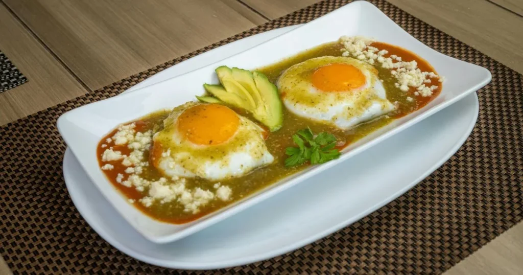 Colorful breakfast plate featuring chilaquiles, eggs, avocado, and fresh herbs.